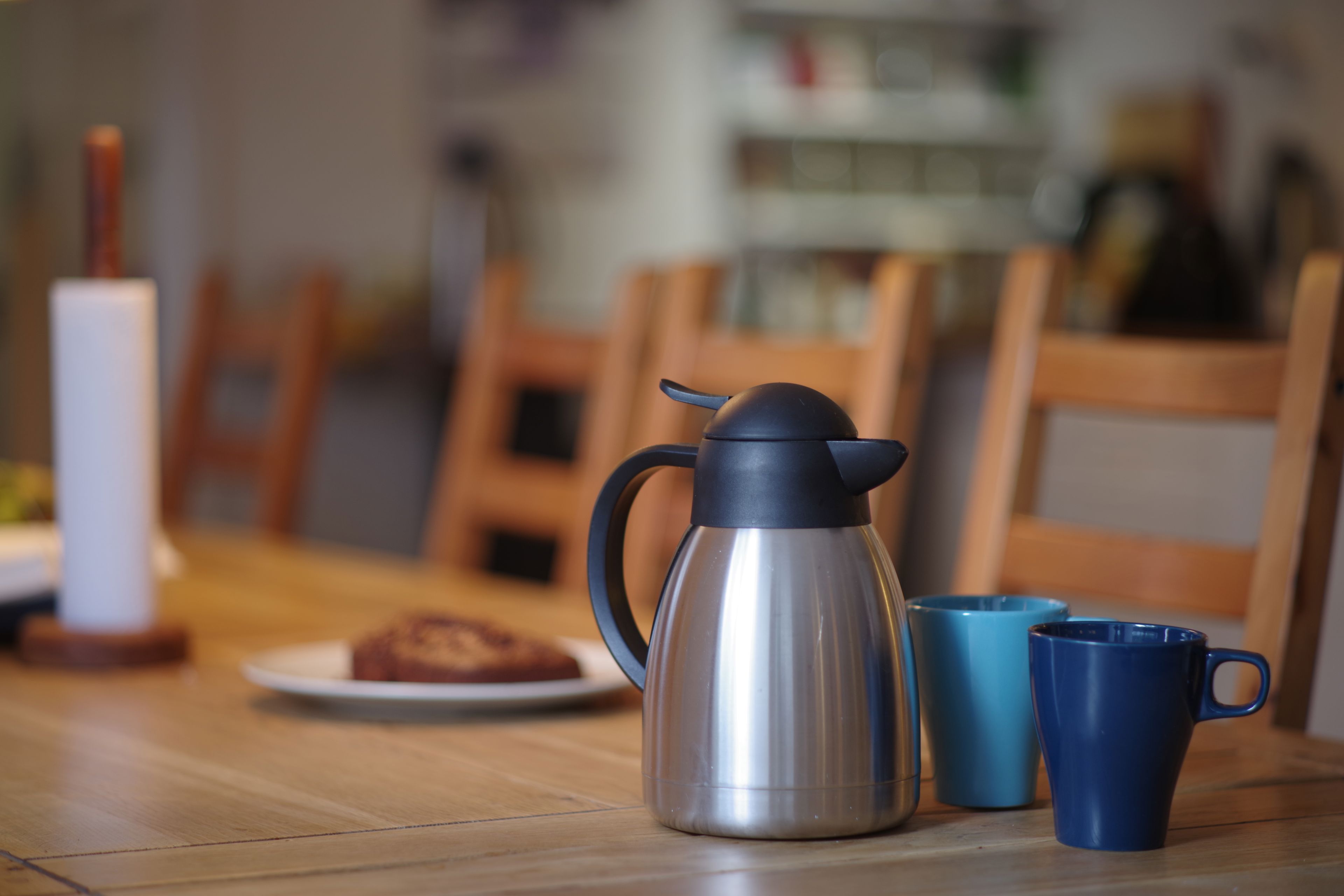 Kaffekande, to blå krus og tallerken med kage på bord